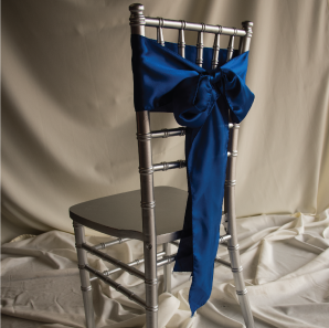 Back of a blue chair sash tied into a bow on a silver chair.