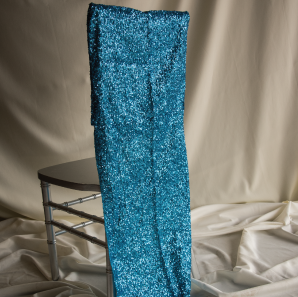 Blue sequined chair cover on a Chiavari chair in front of a white backdrop.