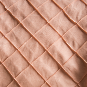Close up of a blush colored pin tuck tablecloth.