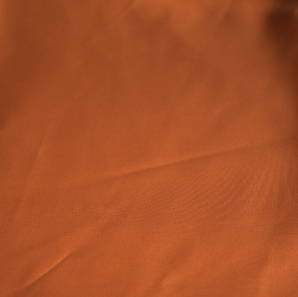 Close up of a burnt orange colored polyester tablecloth.