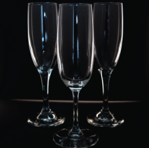 Close up of three champagne glasses in front of a black backdrop.