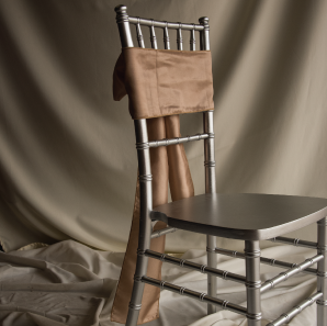 Front of a champagne colored sash tied into a bow on a silver chair.