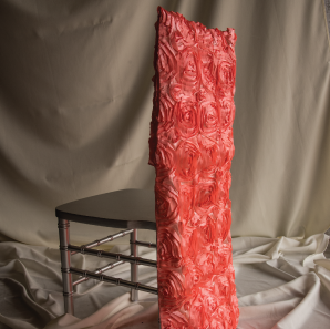 Coral colored rosette chair cover on a Chiavari chair in front of a white backdrop.
