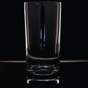 Close up of a highboy glass in front of a black backdrop.