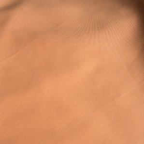 Close up of a peach colored polyester tablecloth.