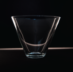 Close up of a stemless martini glass in front of a black backdrop.