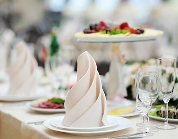 Pink napkin folded into a decorative tower on a nicely decorated table.